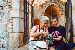 Stylish young woman showing photography to older woman on stony steps