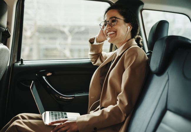 Businesswoman traveling in a taxi with laptop