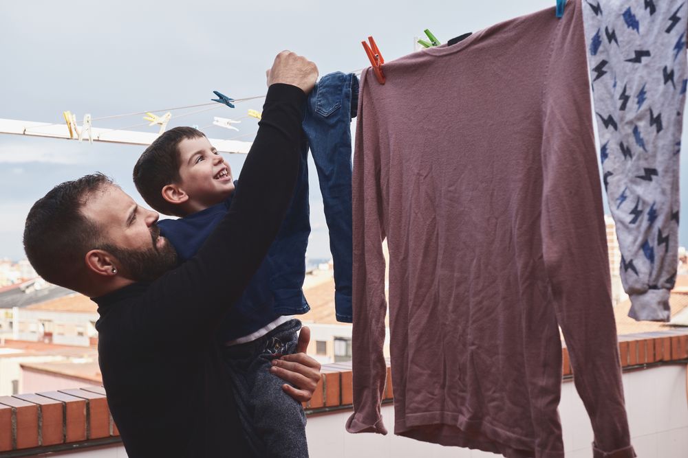 Father and son hanging clothes on rope
