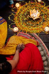 Top view of Indian woman sitting beside Rangoli with candles beMG6b