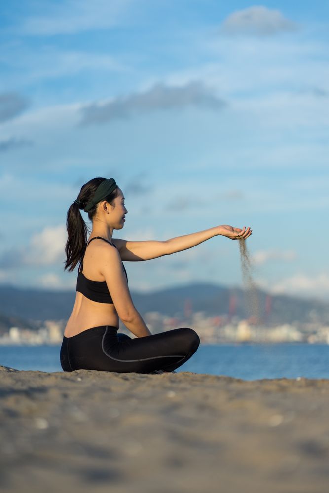 Sportive woman pouring sand through fingers on beach