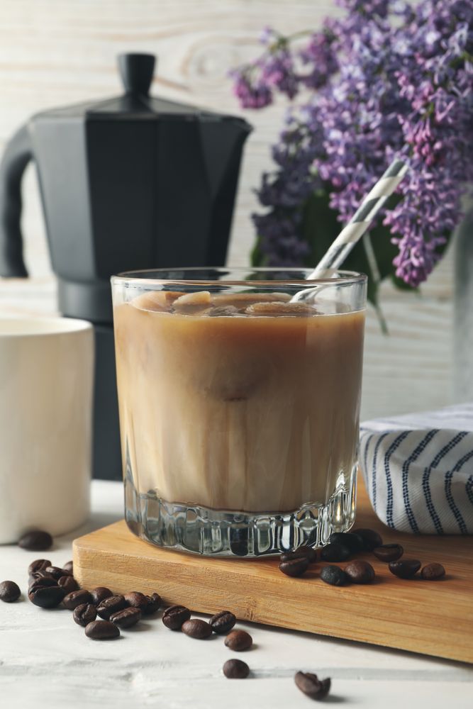 Composition with ice coffee and flowers on wooden background