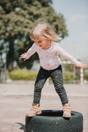 Cute girl balancing on car tires