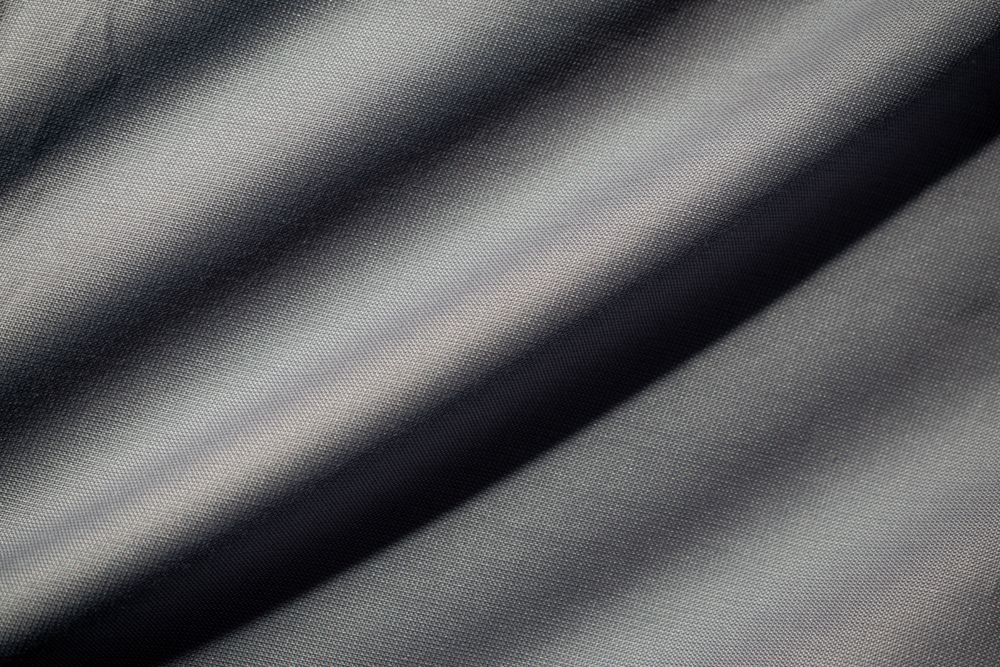 Wavy dark grey fabric background texture. shiny, glossy and elegant background.