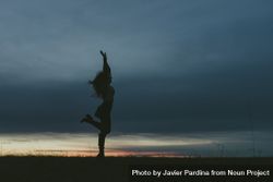 Side view of  woman dancing in a field at dusk 0yXy1b