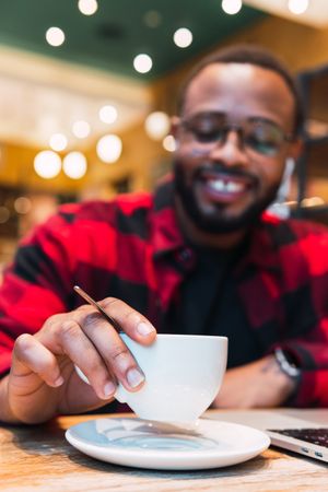 Smiling Black man with cup of coffee in cafe
