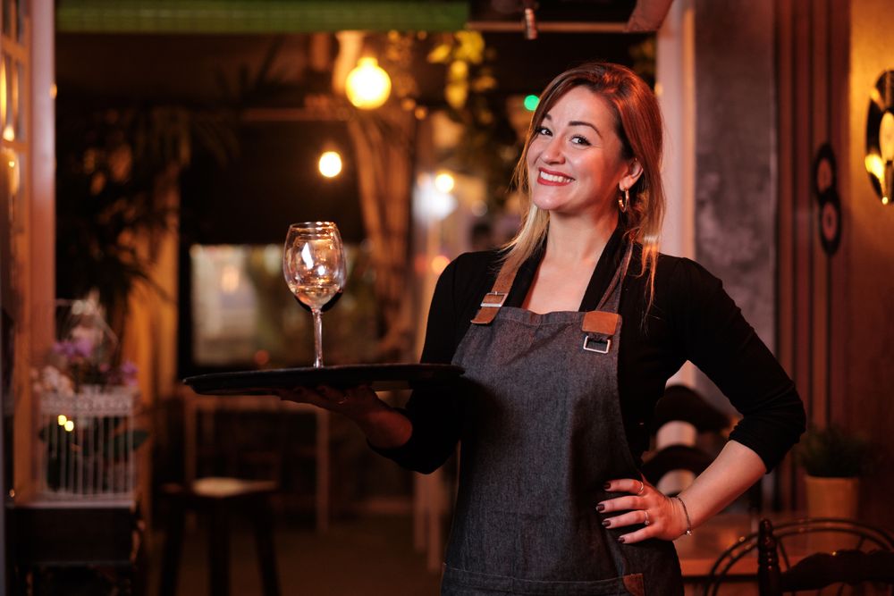 Cheerful waitress holding tray with wineglasses