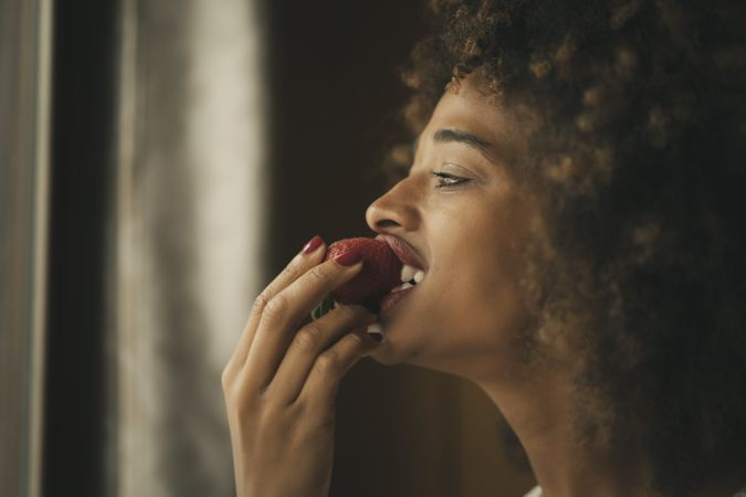 Black woman biting strawberry