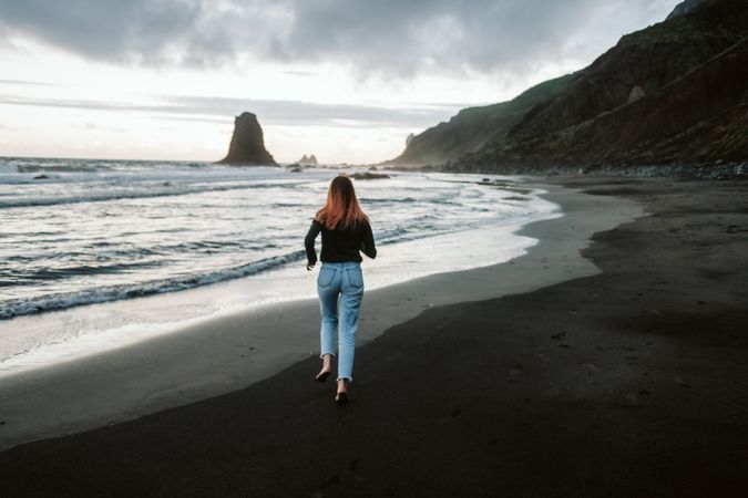 Barefoot female running near waving sea