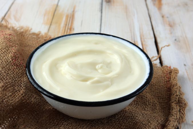 Greek Yogurt in a Enamel Bowl with on Rustic Wooden Plate.