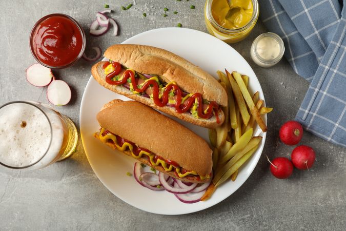 Tasty hot dogs, beer and fries potato on gray table