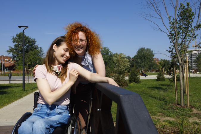 Two woman leaning on rail in park