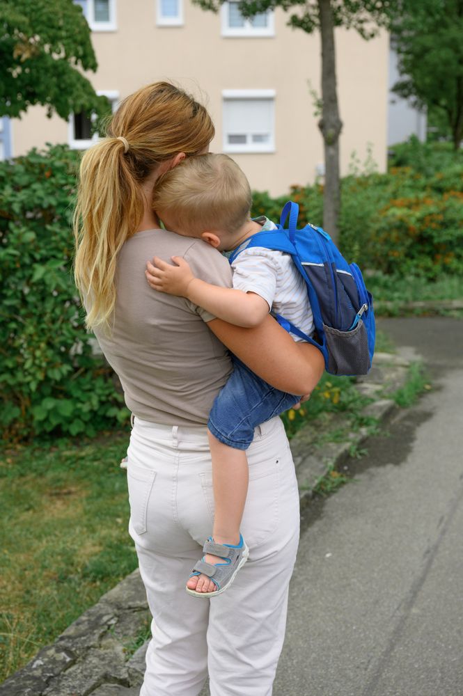 Unrecognizable mother standing and carrying anonymous kid in hands