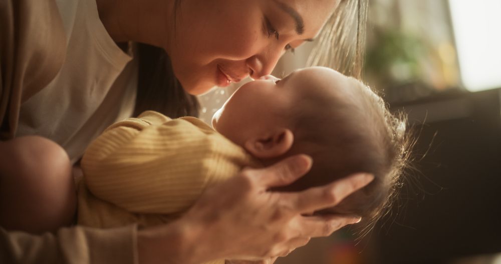 Motherly Affection Concept: Close Up Portrait of an Asian Woman New to Motherhood Having Special Moment with Infant.