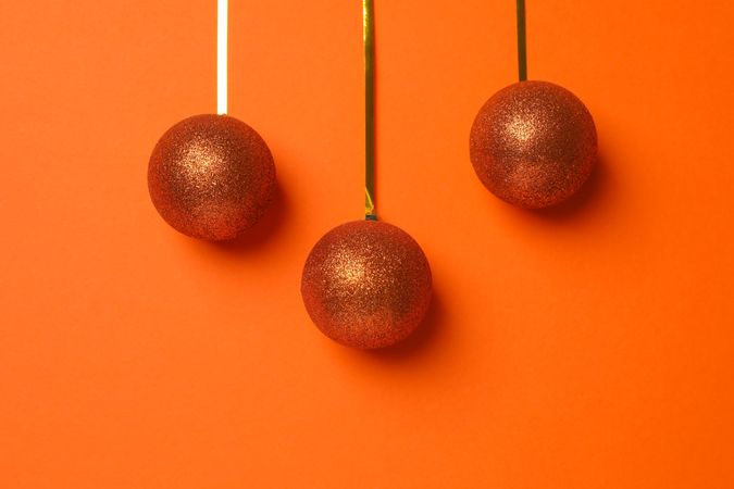 Christmas balls on orange background, space for text