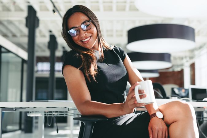 Successful businesswoman smiling in her office holding coffee mug