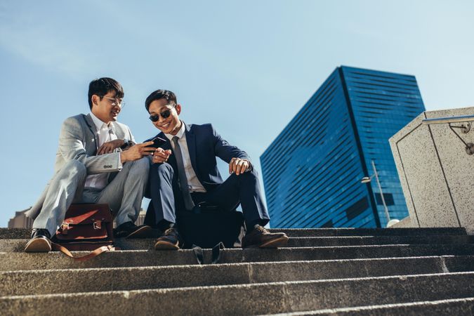 Two young men smiling while looking at smart phone