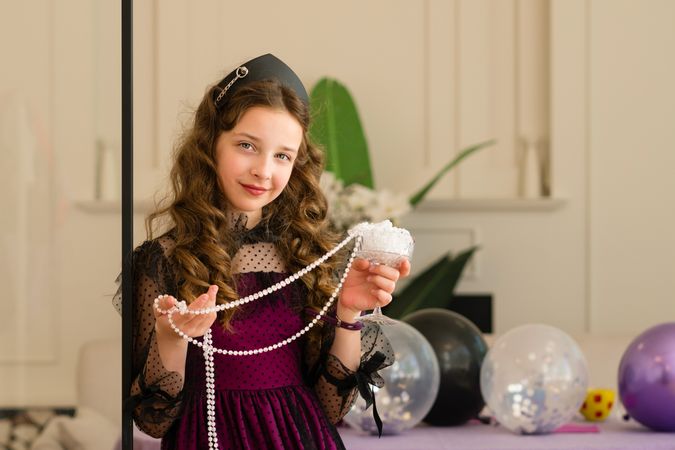 Girl holding pearls and smiling at birthday celebration.