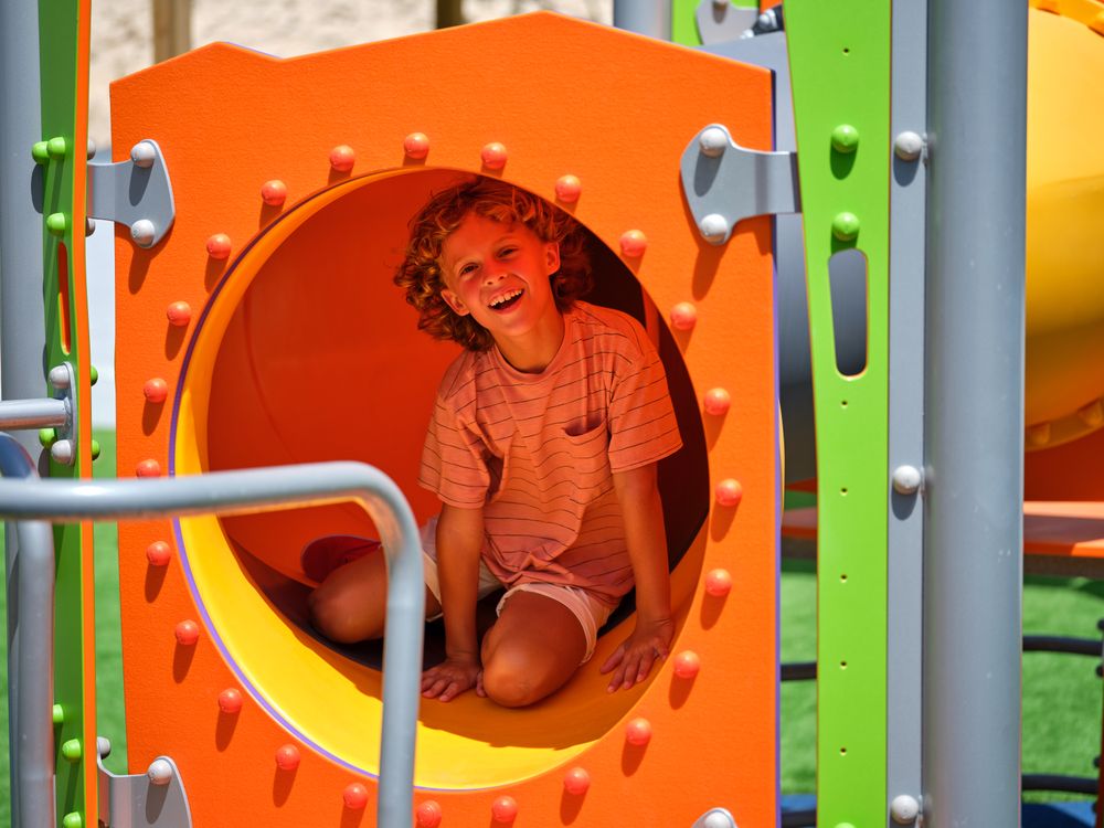 Cheerful boy sitting in tube on playground