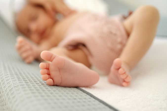 A close up of a baby laying on a bed