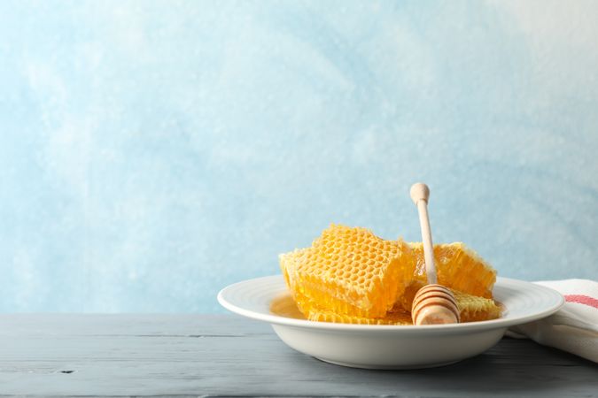 Plate with dipper and honeycombs on wooden background, space for text