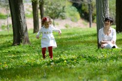 Woman smiling and watching girl walk in sunny park