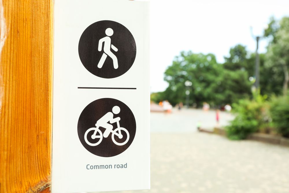 Sign for pedestrians and cyclists in park, space for text