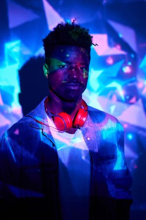 Black man with headphones standing in neon lights