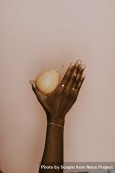 Black hand holding a pear wearing a gold jewelry 47parb