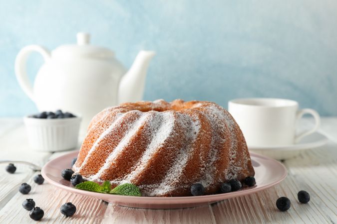 Cake with powder sugar and blueberry on wooden background, space for text