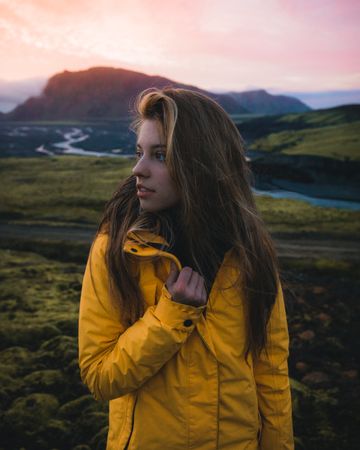 Portrait of young woman in yellow jacket in green natural landscape