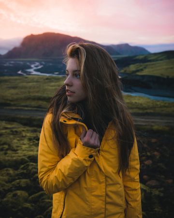 Portrait of young woman in yellow jacket in green natural landscape