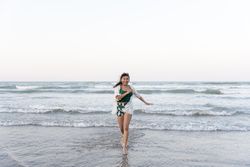 A young Hispanic woman is running from the sea towards the camera at the beach