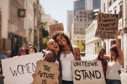 Young women holding banners and laughing during women march