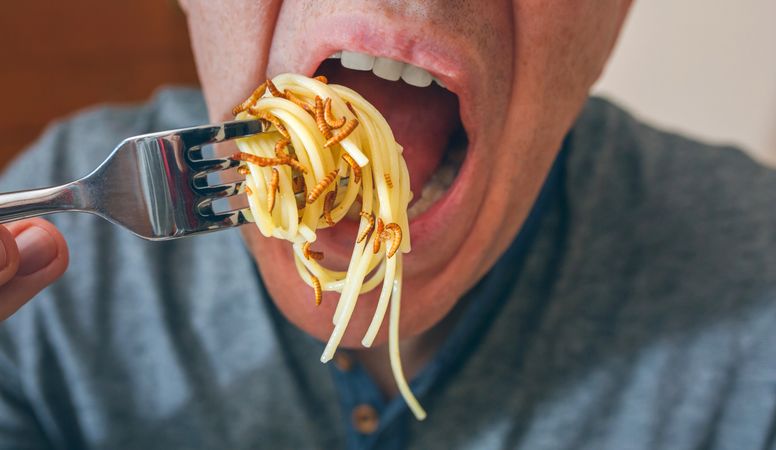Man eating spaghetti with worms