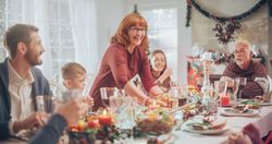 Diverse Group of Relatives and Friends Sitting Together Behind a Dining Table with Tasty Meals and Festive Decorations.