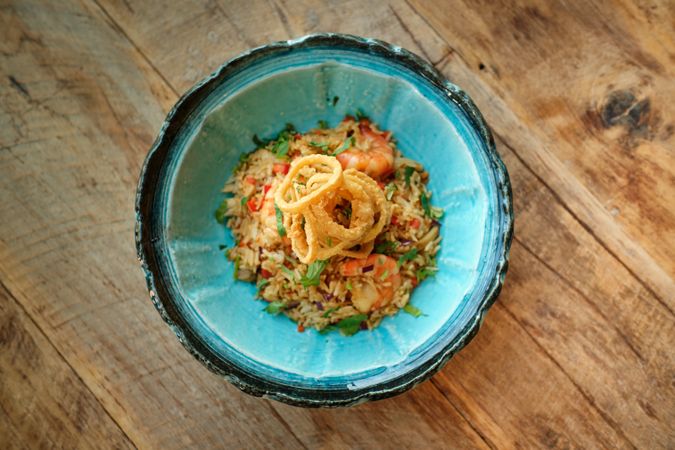 Bowl of delicious fried rice with shrimps on wooden table