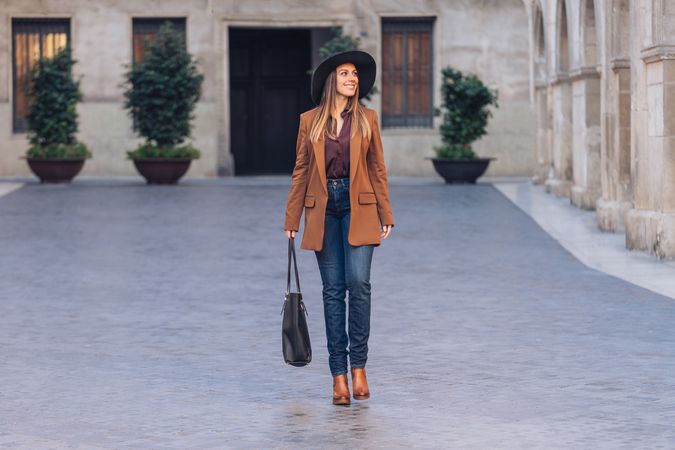Gorgeous woman in fashionable outfit strolling on city street