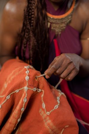 Close-up shot of African woman making embroidery with cowrie shell