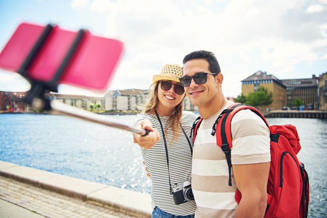 Happy couple with selfie stick taking a picture near a river