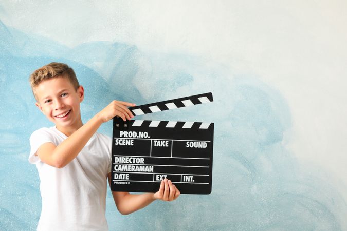 Boy with clapperboard against color background, space for text