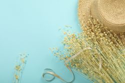 Dried flower bunch on blue background with hat and ribbon with copy space