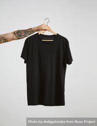 Arm holding a dark t-shirt on hanger 5o6n90