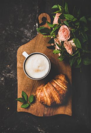 Coffee with croissants and pink roses on wooden board, vertical composition