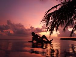 Woman lying in ocean water in sunset