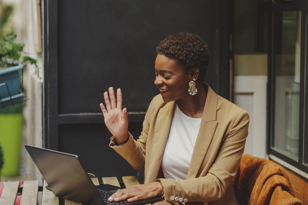 Smiling Black woman sitting at table with laptop in cafe