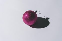 Pink Christmas ornament with pastel grey background and deep shadows