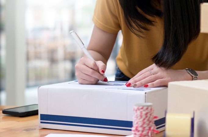 Female writing the address on the box to deliver the package, transport parcels.