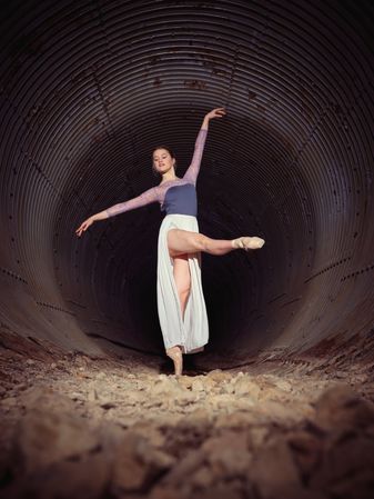 Flexible woman dancing ballet in old tunnel