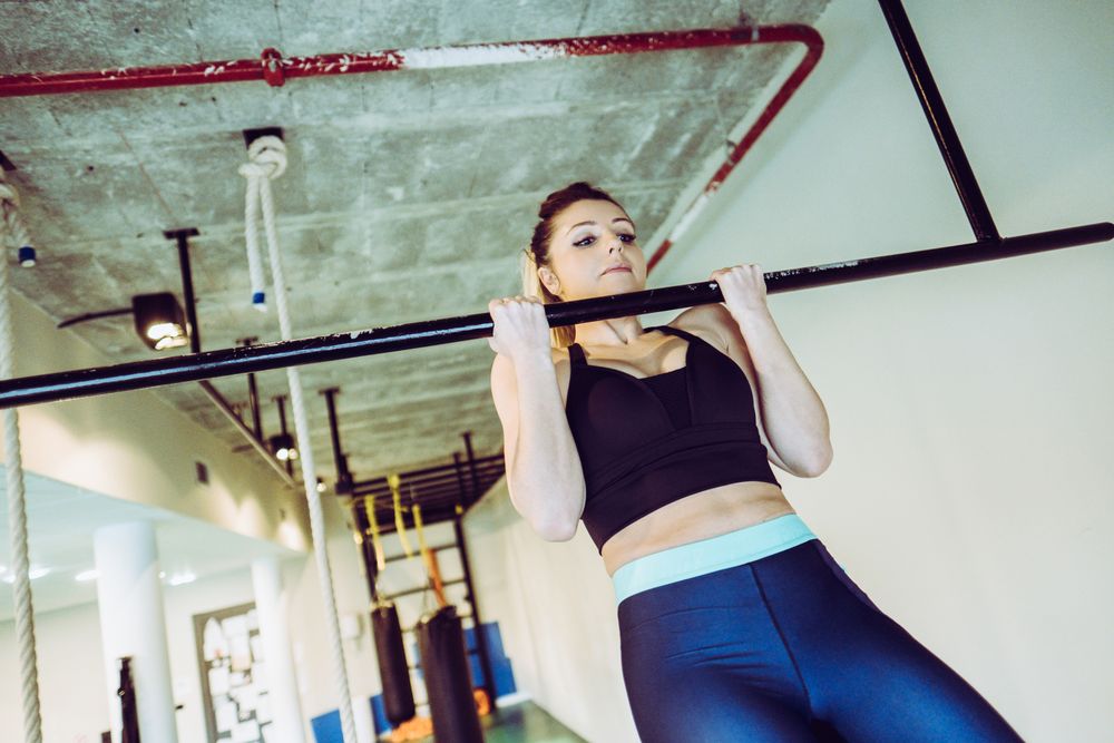 Young woman doing pull ups in gym